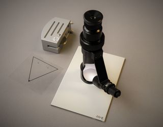 The picture presents the Buchholz hardness tester with a template and the hand-held microscope for the examination of the indentation pattern.