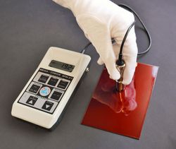The figure shows the coating thickness gauge in use. The sensor is placed by hand upright on the layer to be measured.