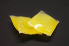 Das Bild zeigt Schmelzklebstoff in Kissenform. Es sind zwei gelbe Kissen abgebildet.