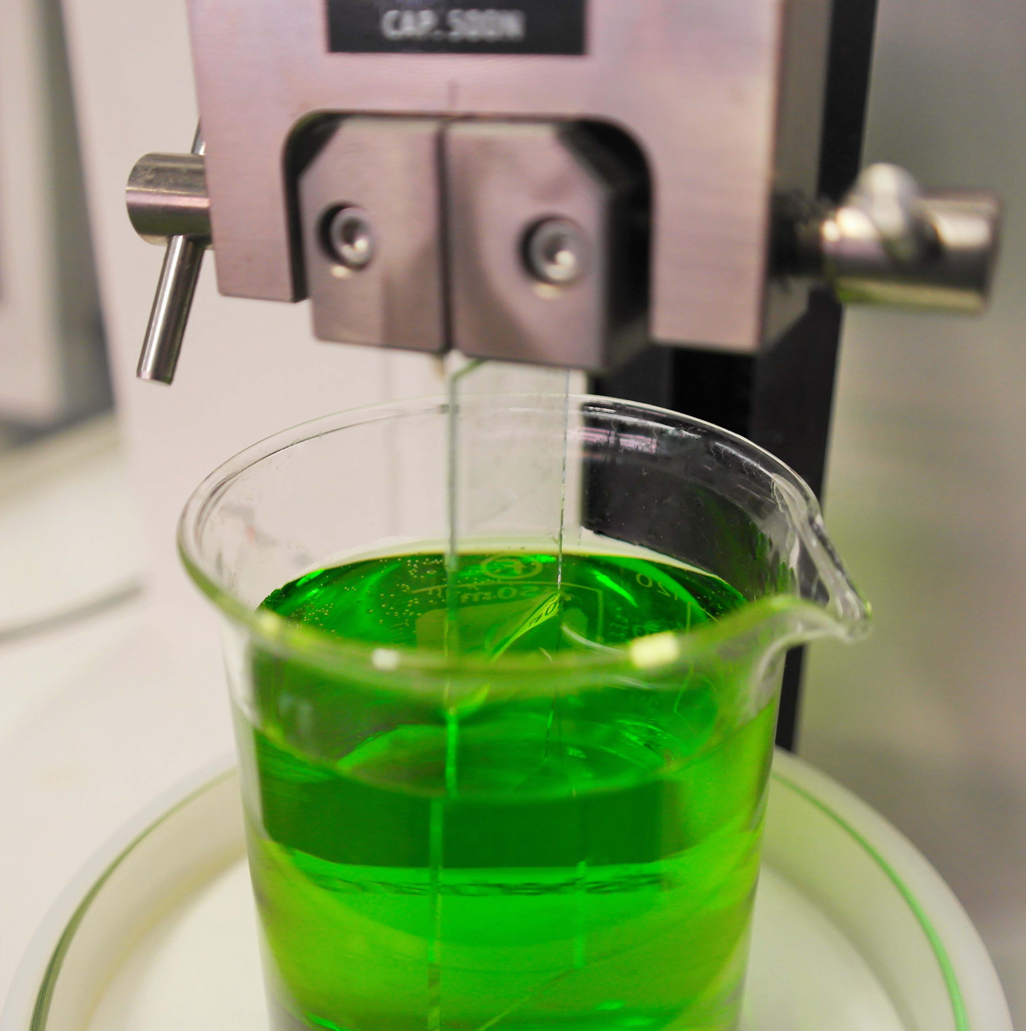 Es erfolgt eine Tauchbeschichtung einer Glasprobe in einer grünen Flüssigkeit.